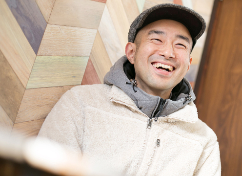 帽子を被り笑顔の天野琢也さんの顔を下から写した写真
