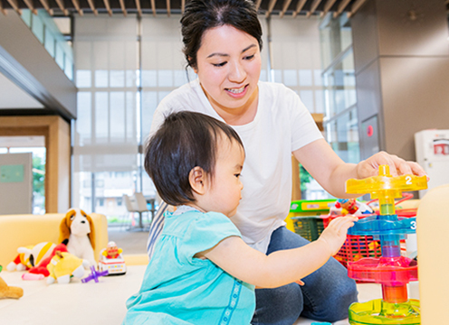 沢山のおもちゃの中お子さんと遊んでいる星野由紀さんの写真