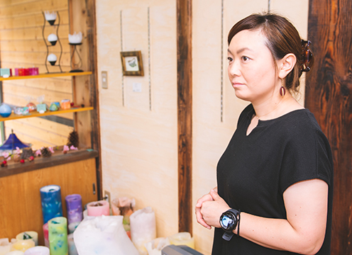 沢山のキャンドルの前で日光移住インタビューを受けている室町悦江さんの写真