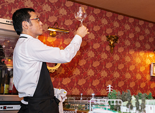 ワイングラスを片手に持ち眺めている小川文男さんを横から写した写真