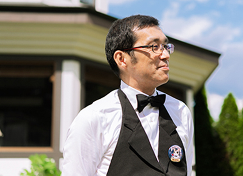 青空の下屋外で日光移住インタビューを受けている小川文男さんの写真