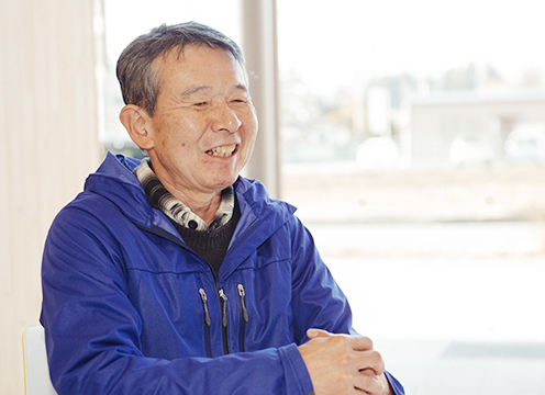 前で手を組み笑顔で日光移住インタビューを受けている山田徹さんの写真