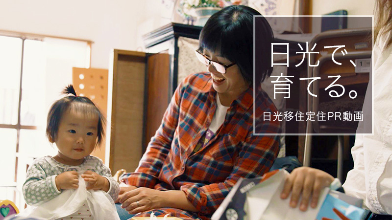 「日光で、育てる。日光移住定住PR動画」の文字と、お母さんが赤ちゃんを見て笑顔になっている様子の写真(住む日光PR動画「日光で育てる」 のページへリンク)
