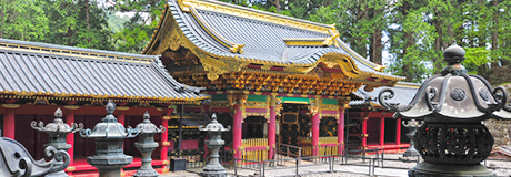 屋根の枠が金色で彩られ、赤の柱が特徴的な日光山輪王寺の門を写した写真