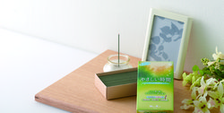 「やさしい時間」と書かれた緑の箱に入ったお線香と香炉にあげられた1本のお線香の写真