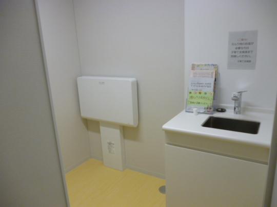部屋の奥におむつ替えの台があり、手前に手洗い場が設置されている写真