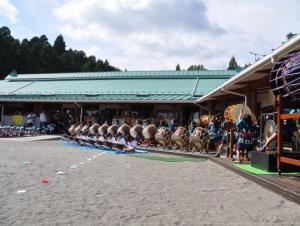 太鼓の練習をしている子どもたちと、エメラルドグリーンの色をした屋根の宝珠保育園園舎の写真