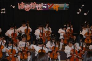 「はるかぜコンサート」と書かれた手作りのボードが設置されたステージで、子ども達がチェロを演奏している写真