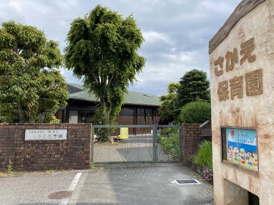 レンガ作りの門があり、植木が植えられたさかえ保育園の正門から撮影した写真