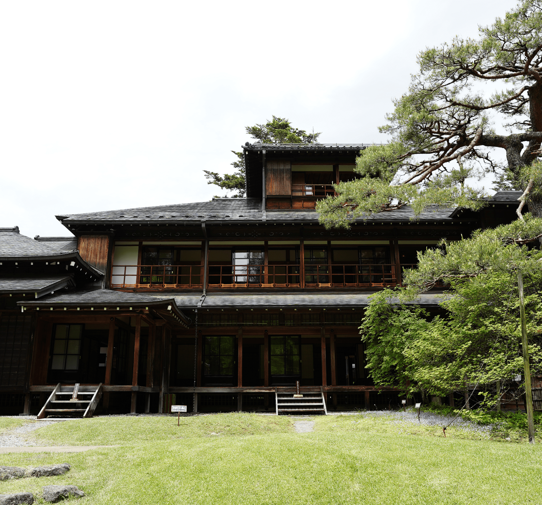 芝生の奥にたくさんの窓がある3階建ての純日本家屋を正面から写した写真