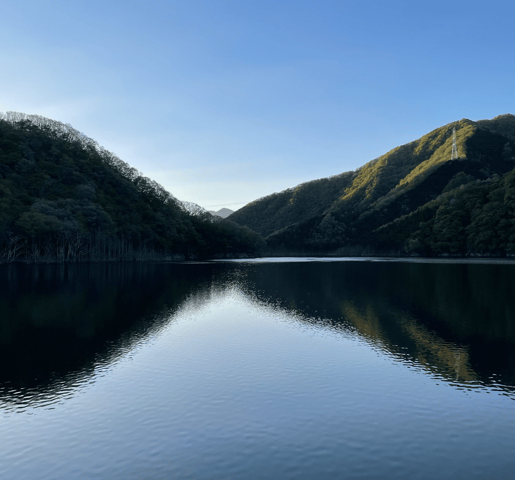 山々がダムの水面に映し出されている湯西川ダム湖の写真