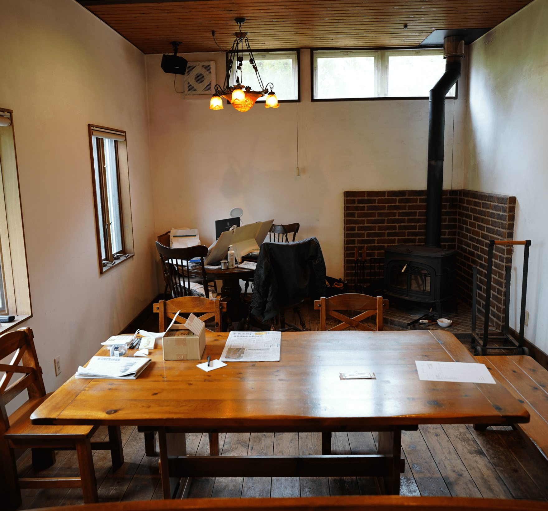部屋の右角に暖炉、丸と長方形の2つの机の上にはいろいろな物が置かれている室内の写真
