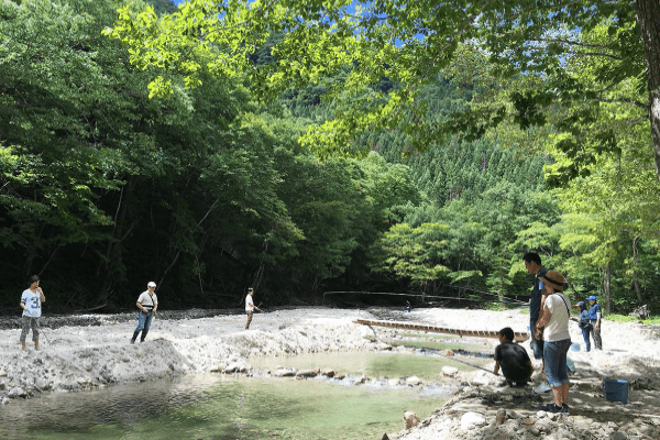 緑豊かな三依渓流つり場で楽しんでいる人たちを写した写真