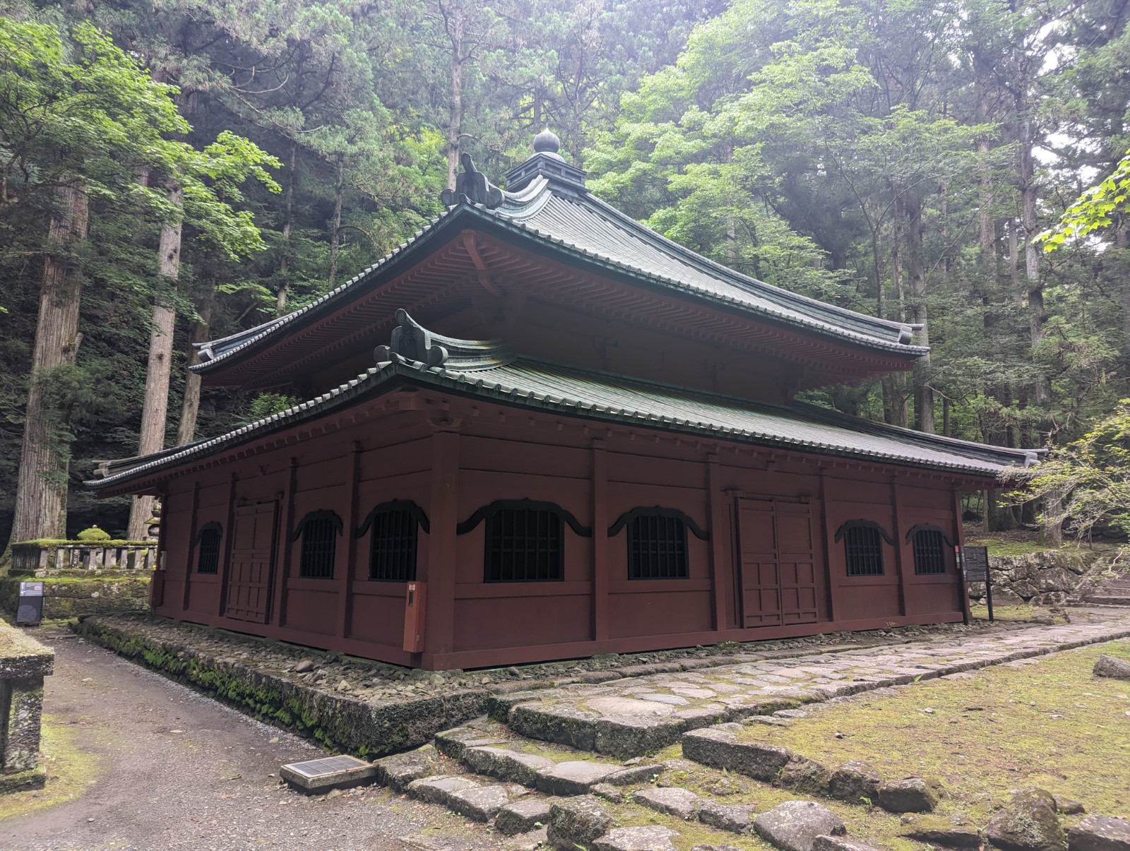 林の中に建つ、朱塗りで重層宝形造りという建築方法のお堂を写した写真