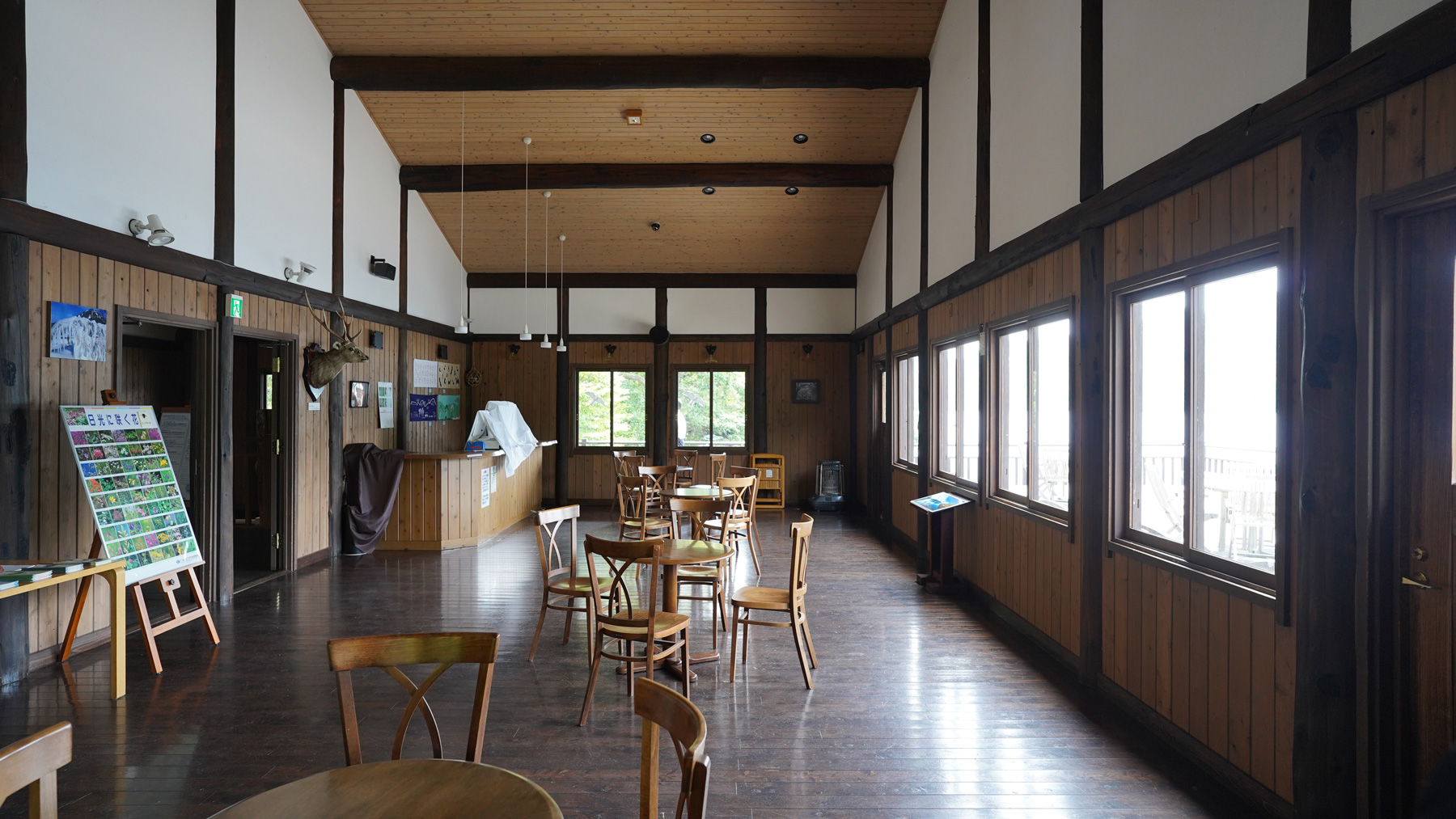 木製のテーブルに椅子がセットされた中禅寺湖畔の喫茶・展望ホールの室内を写した写真