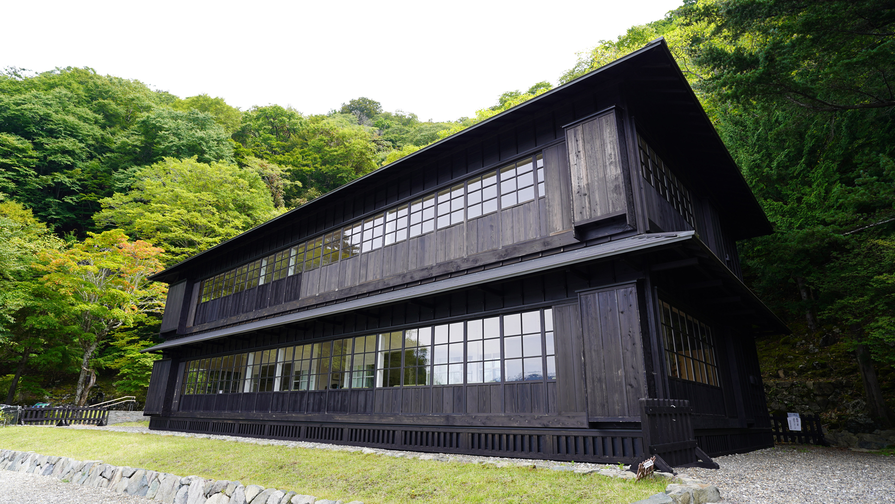 屋根や外壁が全て黒い木材で作られ、長方形の形をした2階建ての英国大使館別荘の外観全体を写した写真