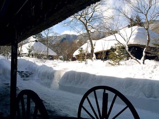古民家の軒から望む雪の積もった古民家の写真