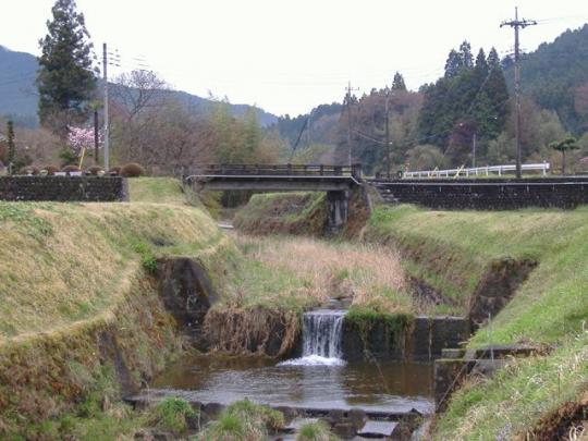 川の土手から土手へ小さな橋が架かっている様子の写真
