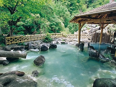 竹の柵で回りを囲まれ緑の木々を眺めることが出来る広々とした加仁湯露天風呂の写真