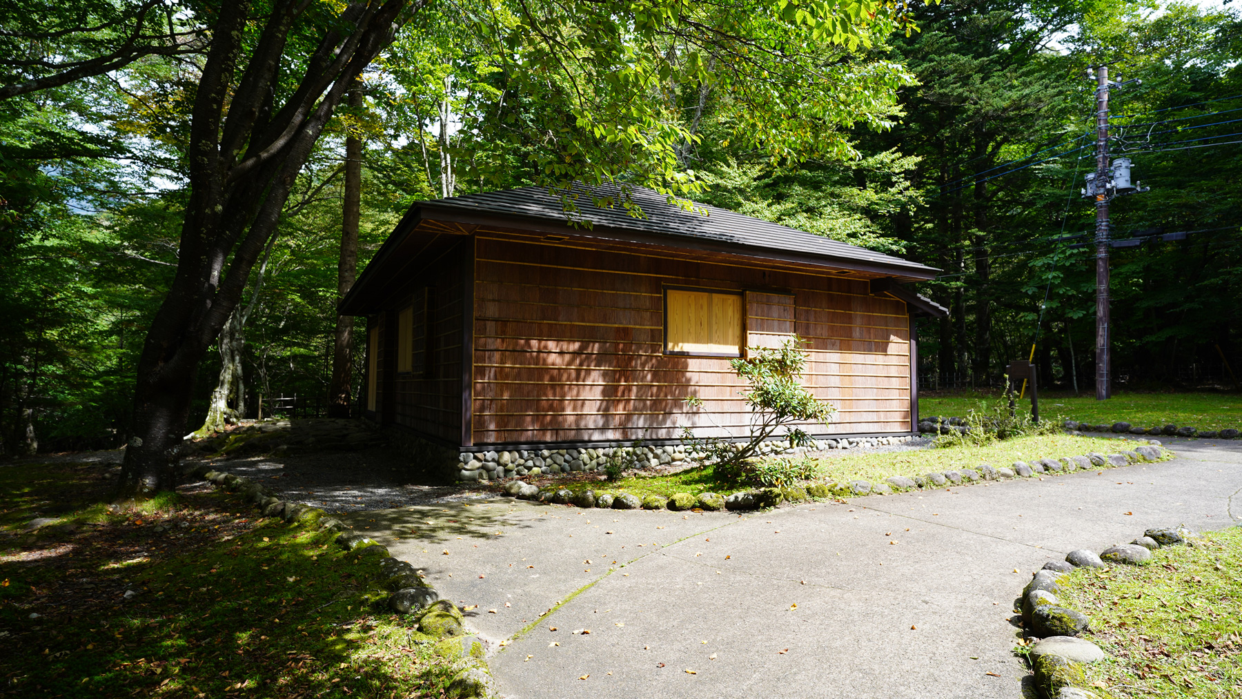 緑の樹木の中に建っている国際避暑地歴史館を湖側から写した写真