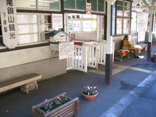 通洞駅の改札口の横で一人の人がベンチに腰をかけている写真