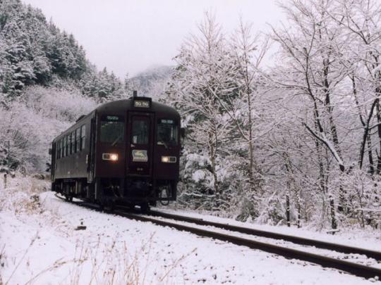 雪の中を一本の線路の上で走っているローカル電車の写真