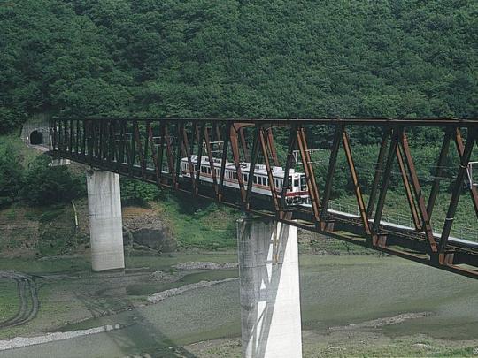 古い陸橋で川を渡る会津鬼怒川線の写真
