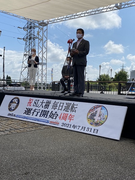 舞台下に「SL大樹毎日運転運行開始4周年」と大きく書かれ、市長が挨拶している大樹4周年記念イベントの様子の写真