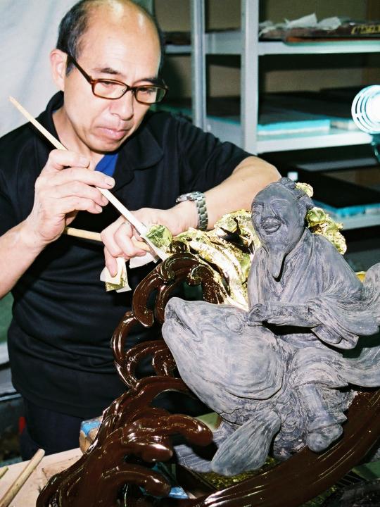 筆を使い作品に漆塗りする佐藤則武さんの写真