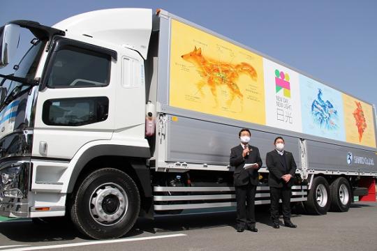 「NEW DAY,NEW LIGHT.日光」の文字や鳥や犬のイラストが描かれたトラックが披露されている写真