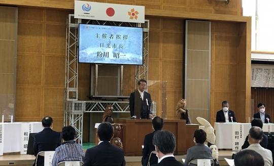 スクリーンに市長の名前が表示され、市長が演壇で挨拶をしている芹沢地区土砂流災害復旧完成式の様子写真