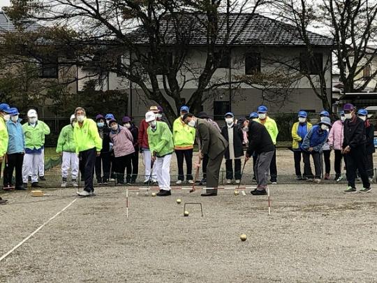 始球式で市長がボールを打った瞬間を周りの参加者の人たちが真剣に見ている写真