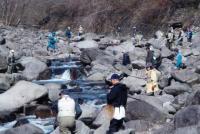 川の両脇に大きな岩がごろごろあり、岩の上に乗って釣りをしている人々の写真