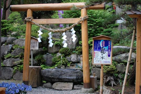 石垣の手前に白木の鳥居のある高龗神社の写真