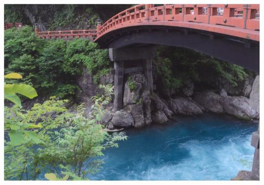 青い川の上に架かる赤い神橋の写真
