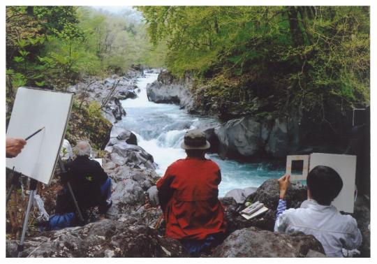 渓谷を、岩に上に腰をかけて絵を描いている人たちの写真