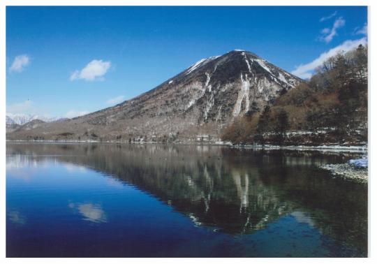 山と水面に山が映し出されている中禅寺湖の写真