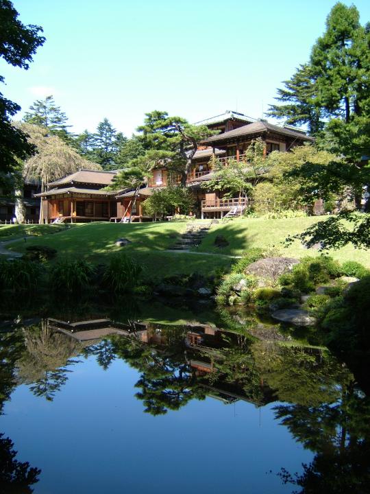 青い空のもと池を臨む田母沢御用邸の写真