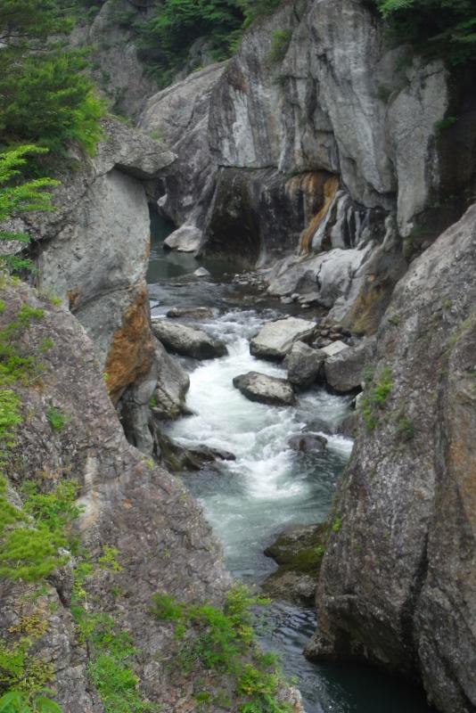 むささび橋から見た岩の峡谷とその間に流れる鬼怒川の写真