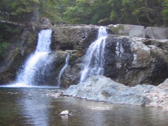 大きな岩の上を二筋に流れ落ちるどんどん滝の写真