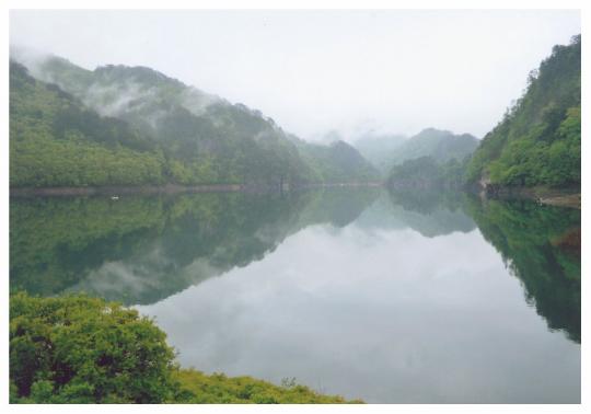 霧がかった山と川俣湖に写る山の写真
