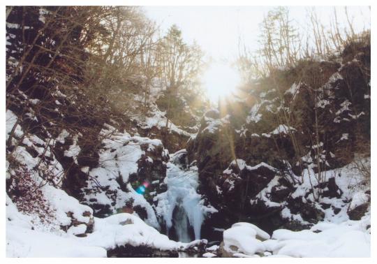 冬の山肌に氷瀑となった大滝の写真