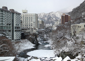 鬼怒川の両脇に建つたくさんのホテルなど全体が雪に覆われている冬の鬼怒川温泉の風景写真