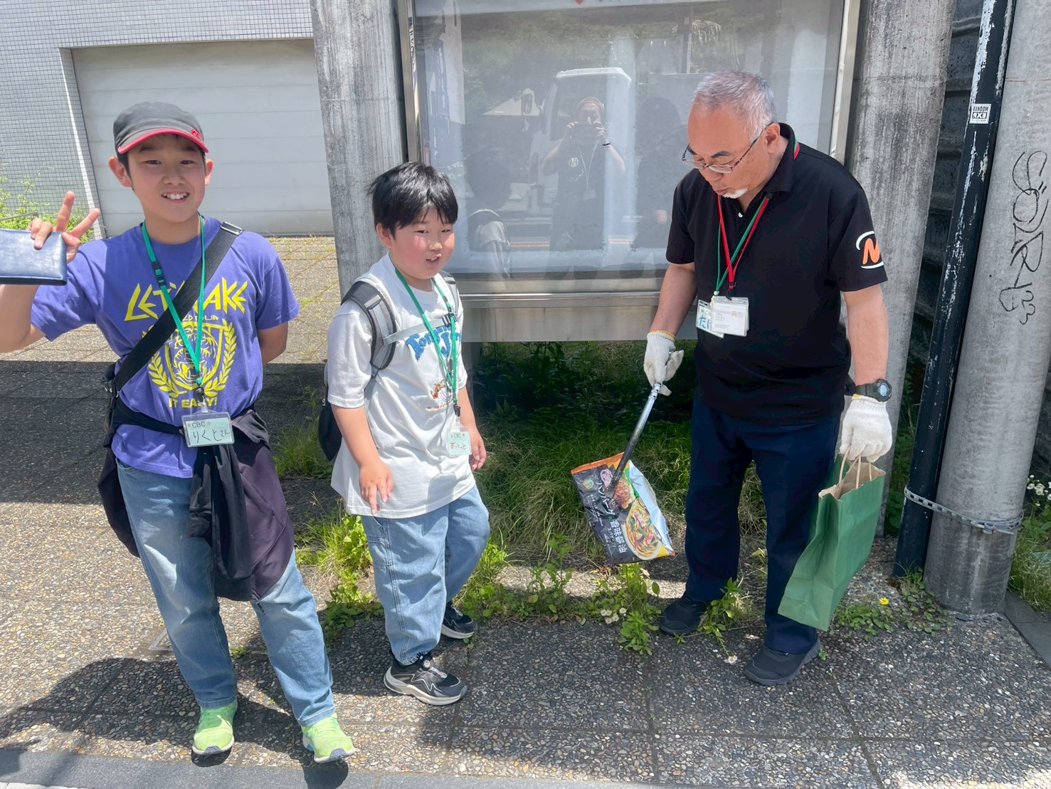 出入口の外に置かれた受付の机の近くに帽子を被った人が立っている写真