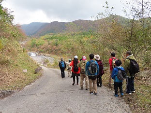 参加者の方々が下り坂を歩きながら、遠くの山を眺めている写真