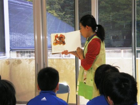 子供たちに絵本を読み聞かせている女性の写真