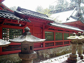 石燈籠の奥にある、朱色で塀の中間部分が緑色の格子上になっている二荒山神社掖門及び透塀の写真