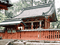 朱色の柵で囲まれた奥に建っている、全体が朱色で切妻屋根の二荒山神社別宮本宮神社本殿の写真