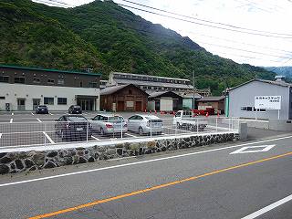 道路に面し、広い駐車場の奥に建っている古河鉱業間藤工場の外観写真