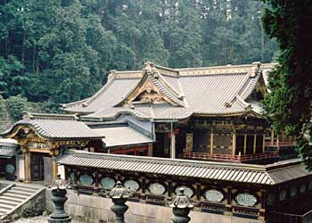 中央が緑色の格子状になっている屋根付きの塀が周りを囲み、塀の中に本殿、相の間、拝殿が建っている写真